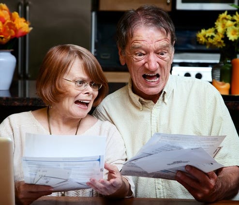 older couple looking shocked, with mouths agape, viewing some papers