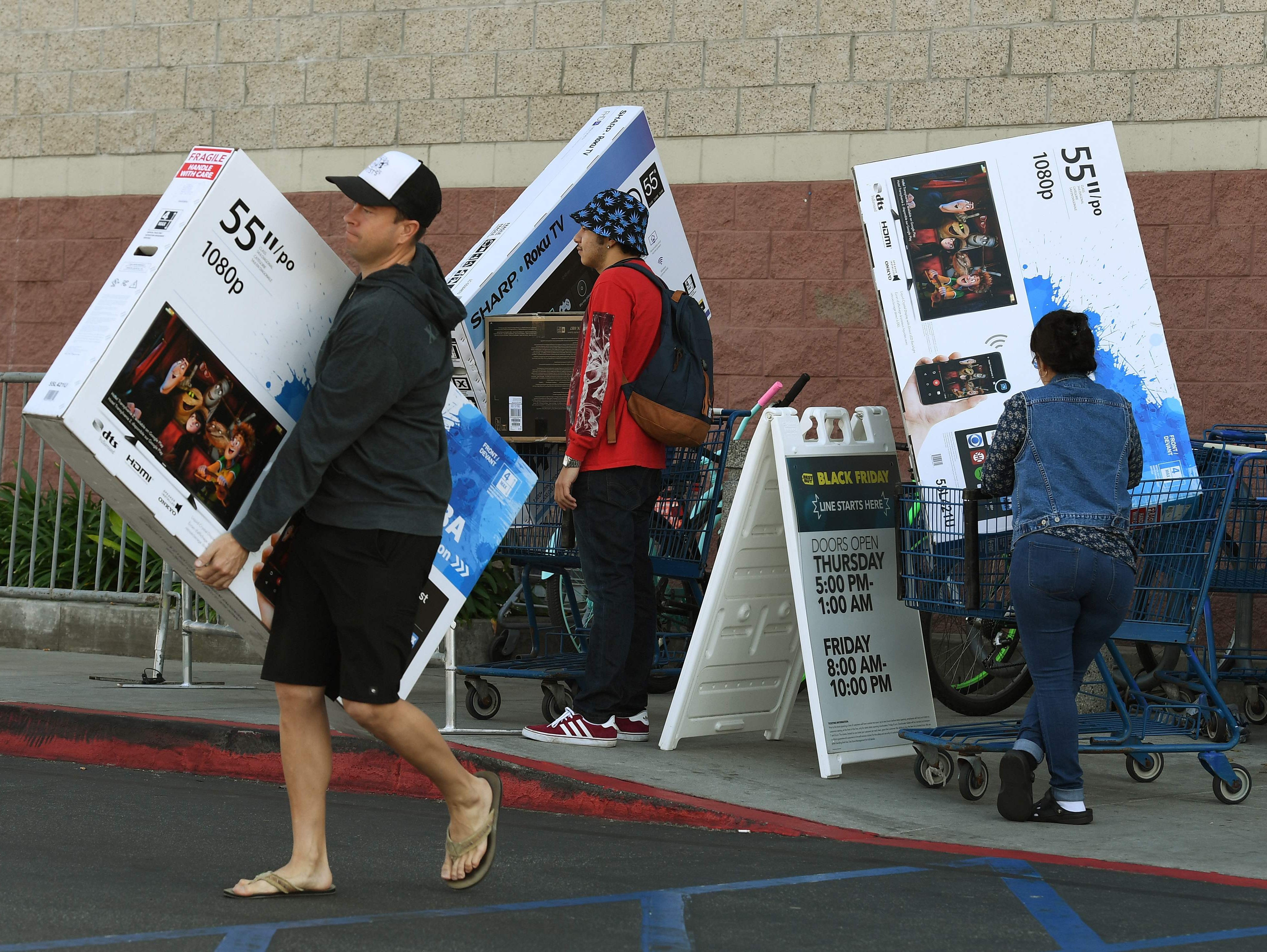 Shoppers with their arms full walk to their cars during the 