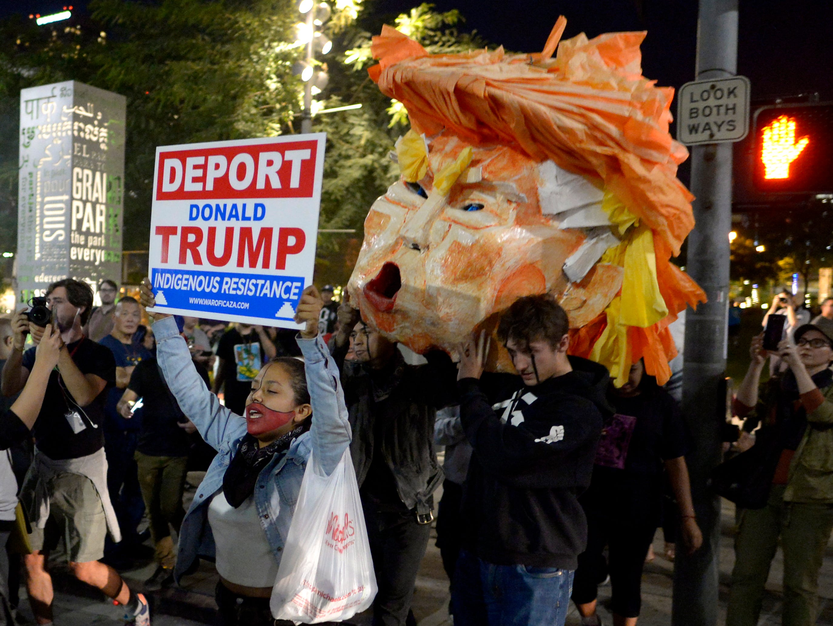 Protesters carry a paper head of president-elect Donald Trump during a protest in front of City Hall Wednesday, Nov. 9, 2016 in Los Angeles.