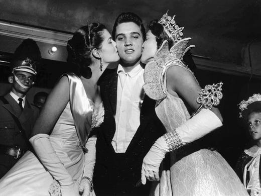 Maid of Cotton Patricia Cowden (left) and Memphis Cotton Carnival Queen Clare Mallory gave Elvis Presley royal kisses just before the rock and roll singer walked on stage before a packed Ellis Auditorium audience on the night of May 15, 1956.