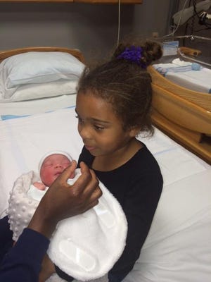 Natasha Laderoot holds newborn baby brother Hayden, who was delivered by Westland Police Sgt. Robert Kenyon in the police department parking lot.