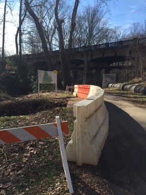 A thick barricade shields users of the Swamp Rabbit Trail near the Cleveland Street bridge from a 10-foot-deep hole caused by a failed stormwater pipe.
