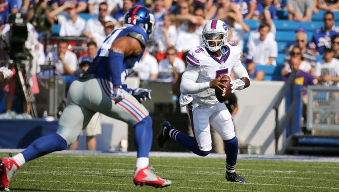 Bills quarterback Tyrod Taylor rolls out looking downfield as Giants Olivier Vernon (54) closes in.