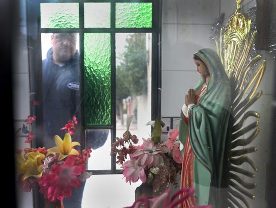 Jorge Garcia looks into a shrine of the Virgin of Guadalupe built by a neighbor. He was deported recently from Detroit and is now trying to adjust to life in a small town outside of Mexico City.