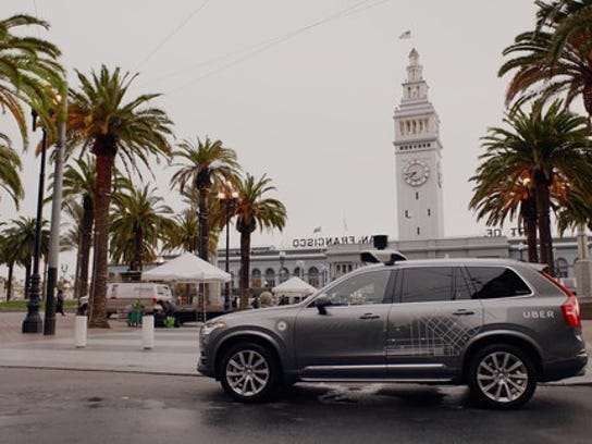 Un Volvo SUV gris con hardware de sensor autoconductor y logotipos de Uber estacionados en una calle de San Francisco.