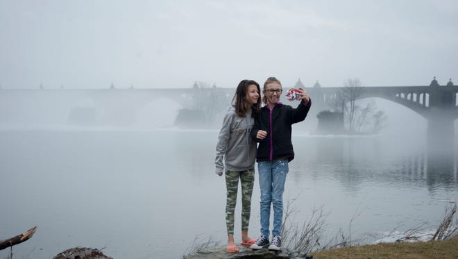 Destiney Mullikin of Manheim Twp., and Ava Lehr of Wrightsville take a selfie with the foggy Columbia-Wrightsville bridge in the background.
