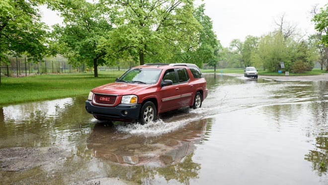 Cars drive through a flooded section of Eliza Howell Park, in Detroit, May 14, 2018.