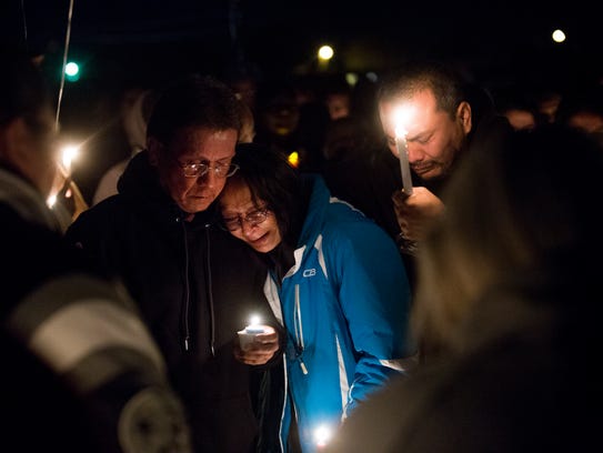 Charles Sam, left, and Anna Sam mourn the loss of Mitchual Sam and Hjordis Sam during a candlelight vigil on Friday in Kirtland.