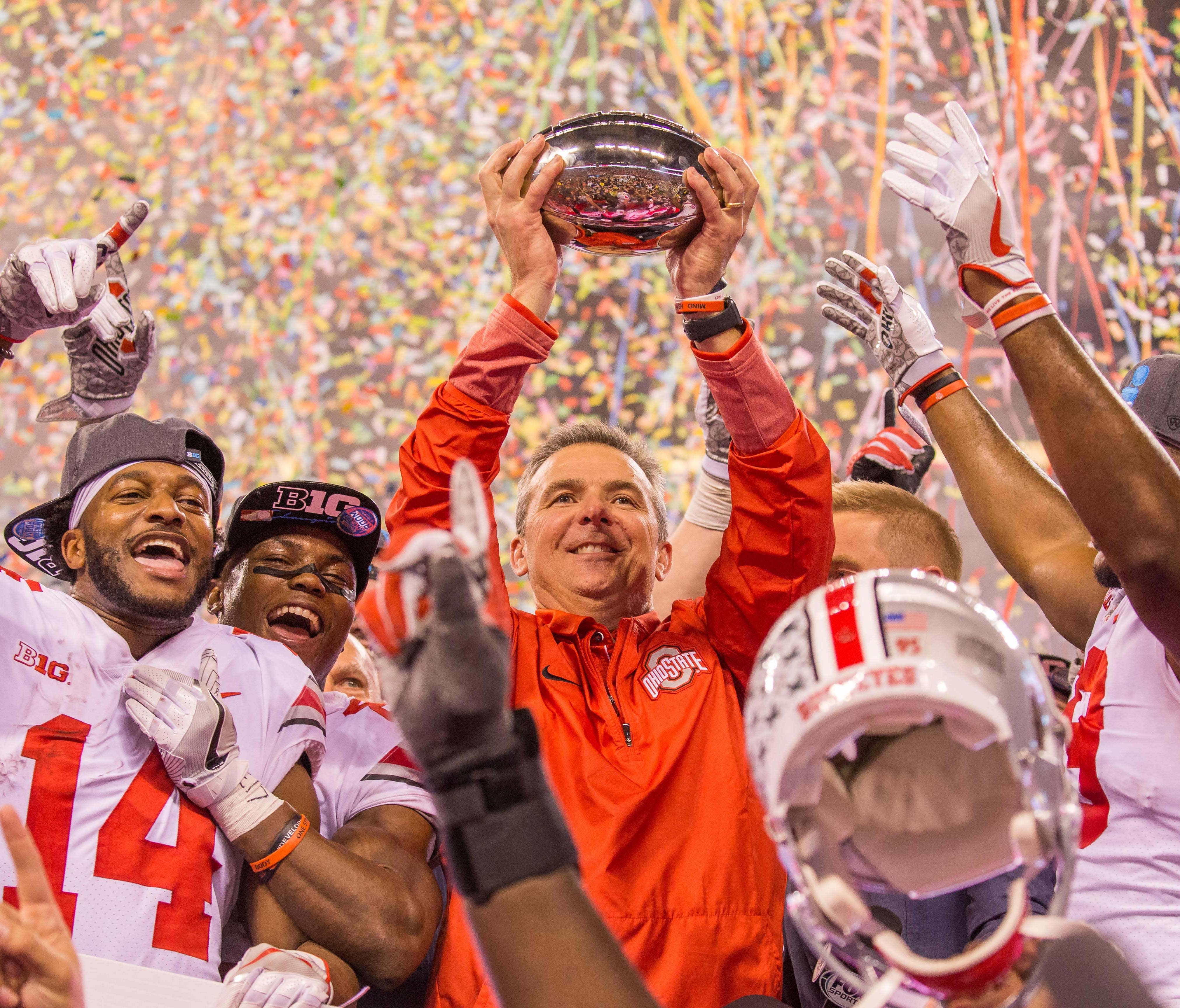 Ohio State Buckeyes head coach Urban Meyer holds up the championship trophy with wide receiver K.J. Hill (14) and his players after the game against the Wisconsin Badgers in the Big Ten championship game at Lucas Oil Stadium.