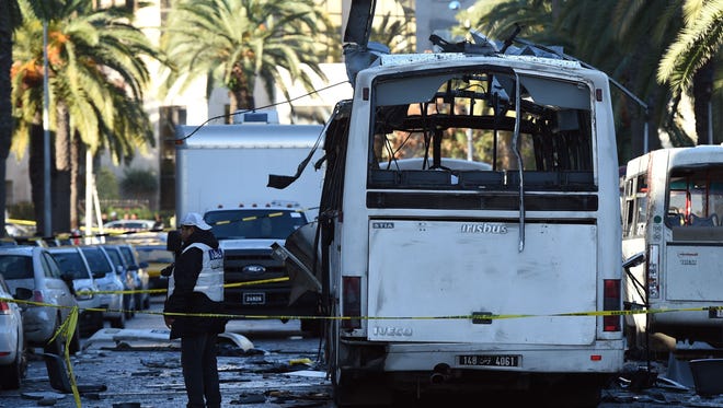 Tunisian forensic police inspect the wreckage of a bus in the aftermath of a bomb attack on the vehicle which was transporting Tunisia's presidential guard in central Tunis on Nov. 25, 2015.