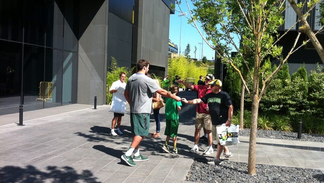 Oregon offensive lineman Tyler Johnstone signs autographs and talks with fans Saturday after practice.