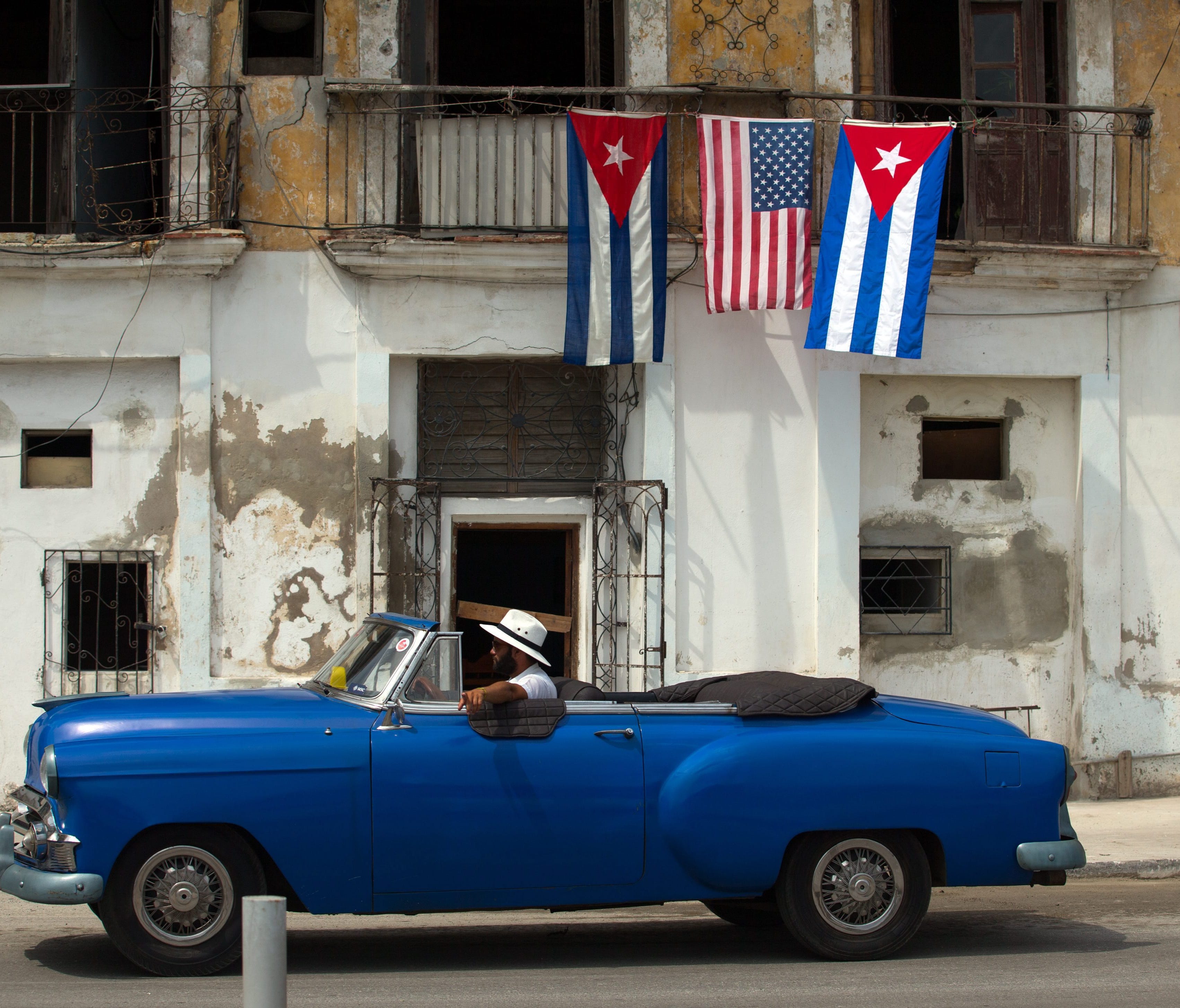 An old car passes by a house decorated with the flags of the United States and Cuba in Havana, Cuba, on March 20, 2016, as the island is preparing for the visit of US President Barack Obama. (EPA/ORLANDO BARRIA)