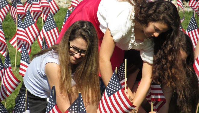 In observance of Memorial Day, each student at Readington Middle School placed a flag on the school's front lawn on May 25. Isabella Guerriero and Gianna Uvari are shown placing flags.