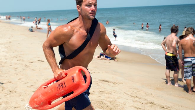 Lt. Mike Thompson, a Dewey Beach lifeguard, patrols a crowded beach Thursday afternoon. Arthur is expected to arrive during one of the busiest weekends of the year.