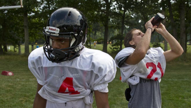 Vincent Lee and Mike Gawlik take a water break during Jackson Memorial practice earlier this summer.