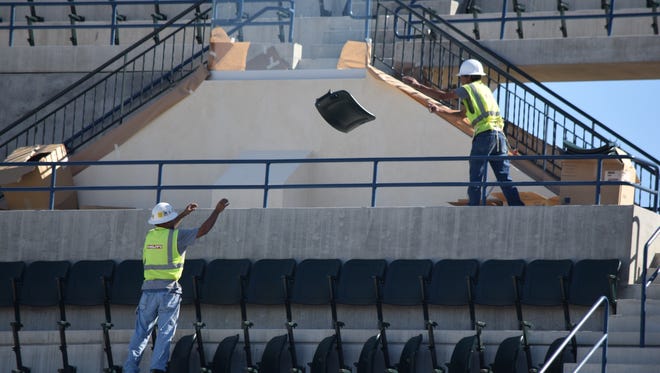 Workers install new chairs in Stadium 1 at the Indian Wells Tennis Garden.