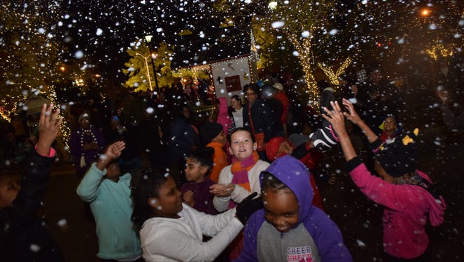 Children enjoy playing in the falling snow at Alex Winter Fete held Thursday in downtown Alexandria. Several snow machines are stationed at various locations.