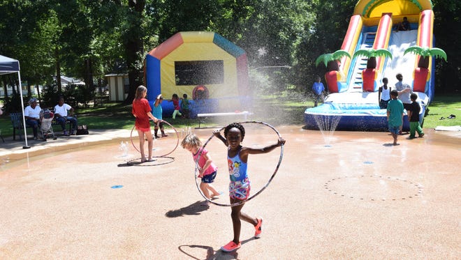 Children play in the splash pad, in the bounce  house and on the water slide at Harmon Park on Tuesday during the Rec2U program's first event of the summer.