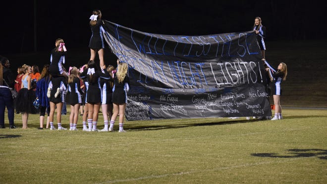 The cheerleaders welcome the Braves to the field last Friday night with a special banner reading "We will miss these Friday night lights!" This was the last home football game of the season.