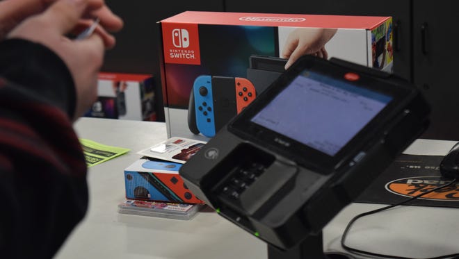 A customer purchases a Nintendo Switch during a midnight release event at Best Buy in York.