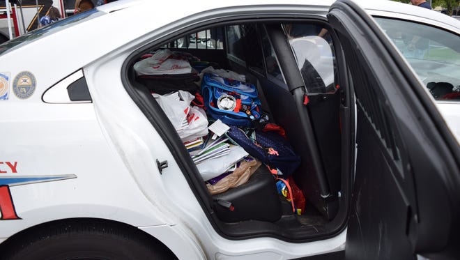 Residents stuff a Tallahassee Police Department patrol car with school supplies .