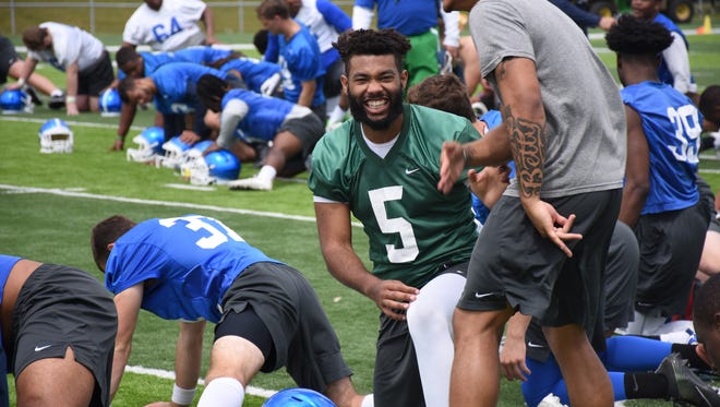 UWF quarterback Kalu Onumah laughs with defensive back Trent Archie during the first day of spring practice on March 24, 2018.