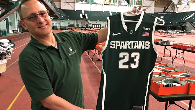 James Ives, Education and Outreach Coordinator for the MSU Surplus Store hold up a game-used Draymond Green jersey that can be yours for the price of $300.