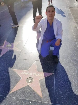 Dr. Eugene Gu, a Vanderbilt University Medical Center surgery resident, kneels on a sidewalk star dedicated to Donald Trump in Los Angeles. Gu says Vanderbilt is essentially firing him because of his outspoken politics and comments on race.