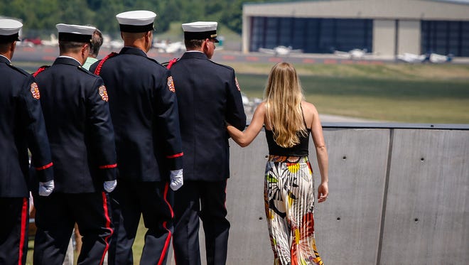 Christina Kuss, wife of Blue Angels pilot Capt. Jeff Kuss, is escorted to the flag poles by a member of the Smyrna Fire Department Honor Guard.