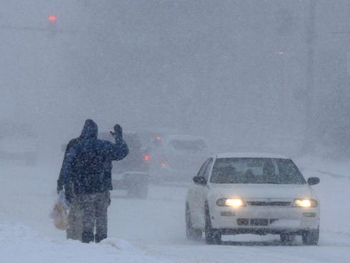 A man waves at a passing car in downtown Elkhart, Ind. on Saturday.