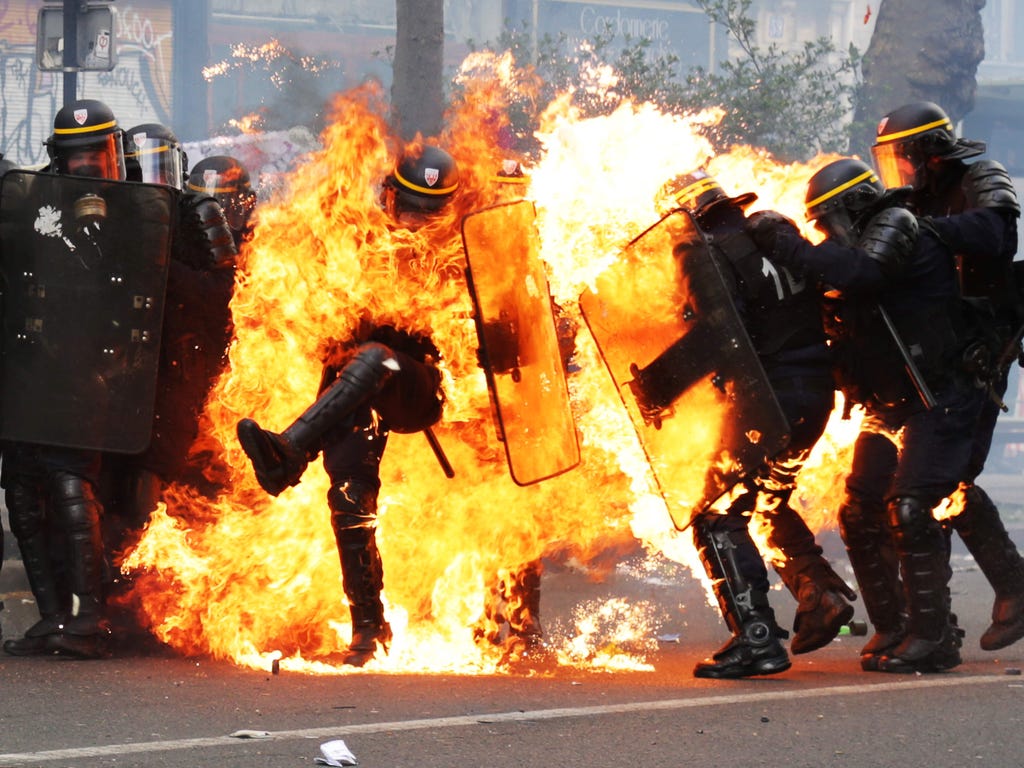 French CRS anti-riot police officers are engulfed in flames as they face protesters during a march for the annual May Day workers' rally in Paris.