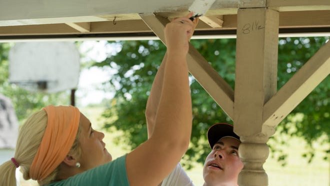 Faith McCraw, 19, of Fancy Gap, Va., left, and Carson Weber, 16, of Rockford, Ill., spread on the white paint on a back porch in Henderson, Ky., Thursday afternoon. They are part of the World Changers group visiting the town to help those in need with home maintenance and even some light construction work.