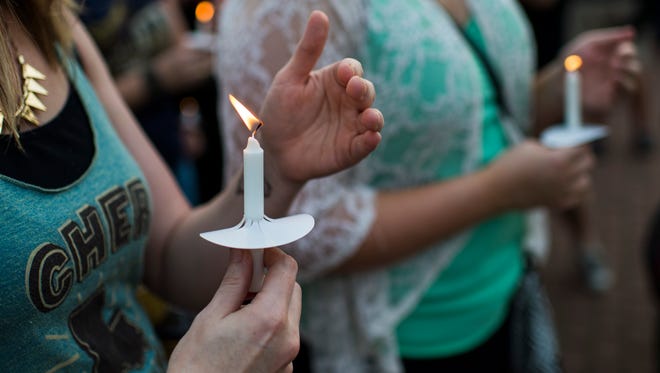 People hold candles during a candlelight vigil for the victims of the Grand 16 Theatre Shooting at Parc Sans Souci in Lafayette, La., Saturday, July 25, 2015. 