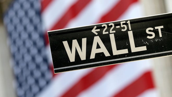 FILE - In this Tuesday, Sept. 8, 2015, file photo, a Wall Street street sign is framed by a giant American flag hanging on the facade of the New York Stock Exchange.