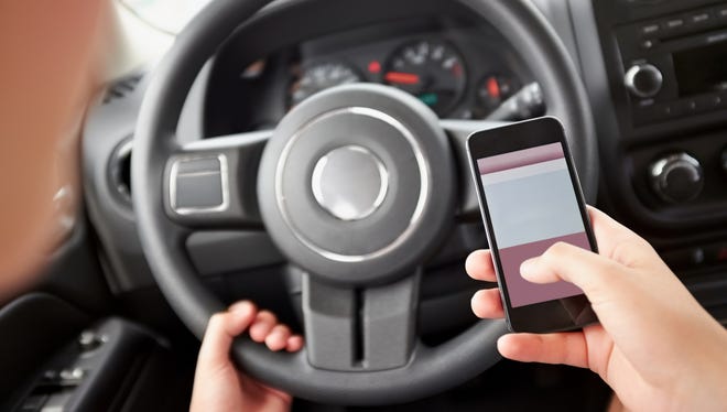 Closeup image of young person texting while driving.