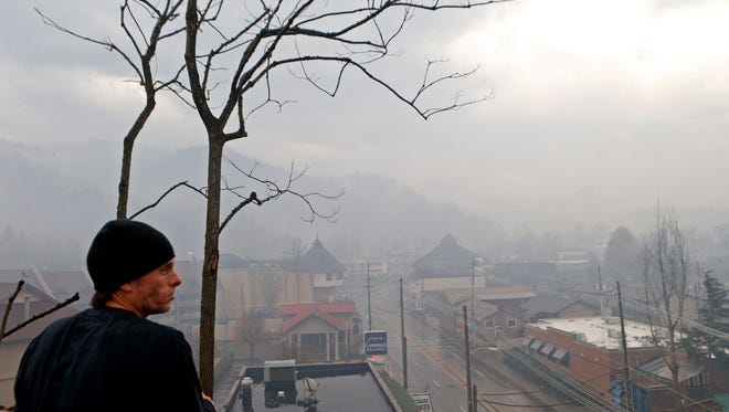 Mark Rowlett finds a high vantage point to survey the damage to structures and woodlands as smoke fills the air and surrounds businesses and resorts in the wake of a wildfire Nov. 30, 2016, in downtown Gatlinburg, Tenn.