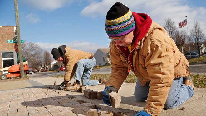 Hank Copeland, foreground, and Mike Carron install brick pavers as they help to construct a pocket park Thursday, December 7, 2017, at Wabash Avenue Ellsworth Street in Lafayette. Both men are with Habitat for Humanity.