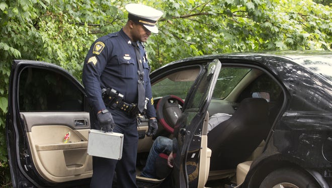 Cincinnati Police Sgt. Ken Hall checks the body in a Ford Fusion in the back parking lot of an apartment in Epworth in Westwood in May 2017. Residents had called the police about a person unresponsive in a car. The cause of death was suspected overdose.