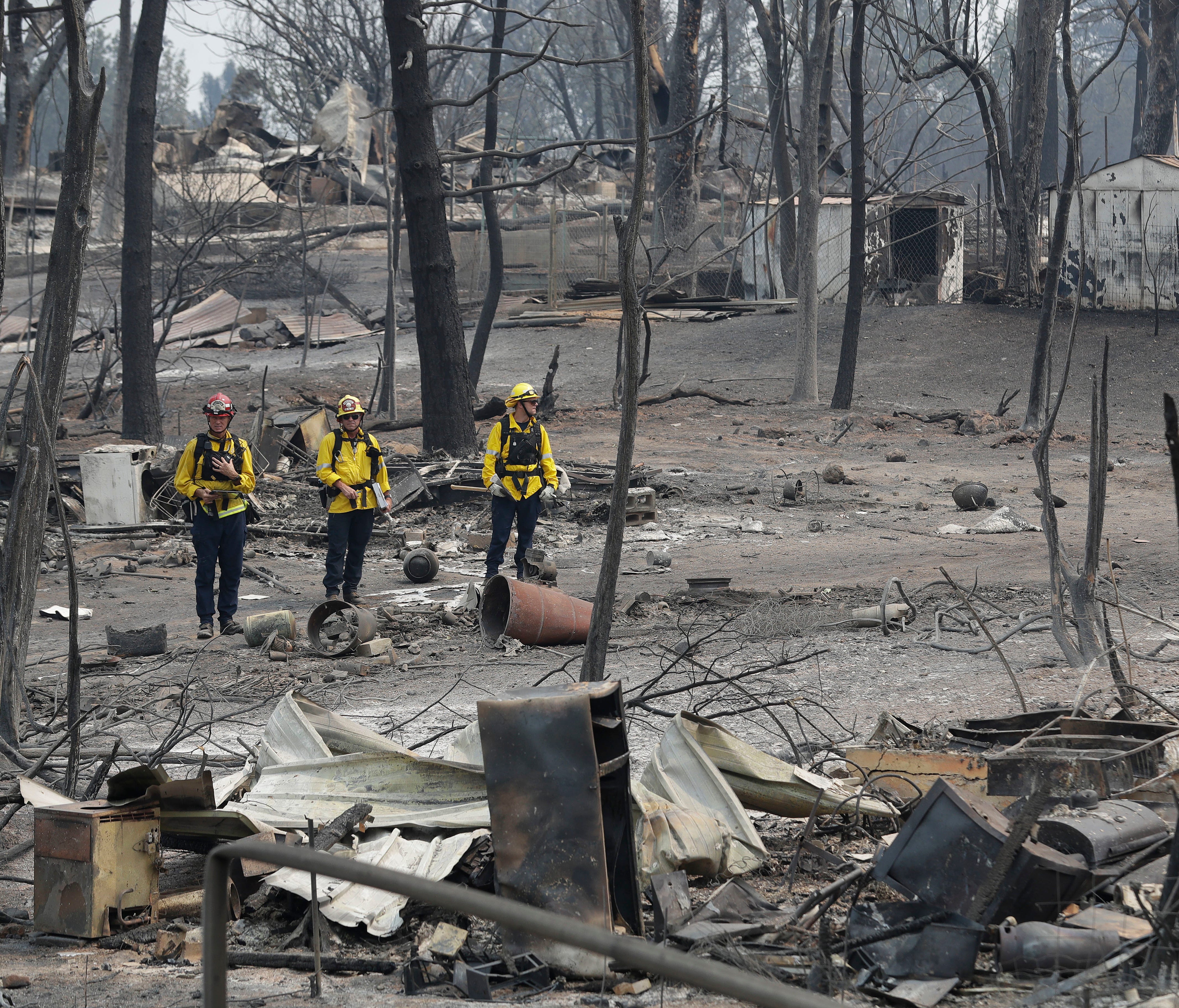 San Bernardino County Fire Department firefighters assess the damage to a neighborhood in the aftermath of a wildfire, on July 29, 2018, in Keswick, Calif.