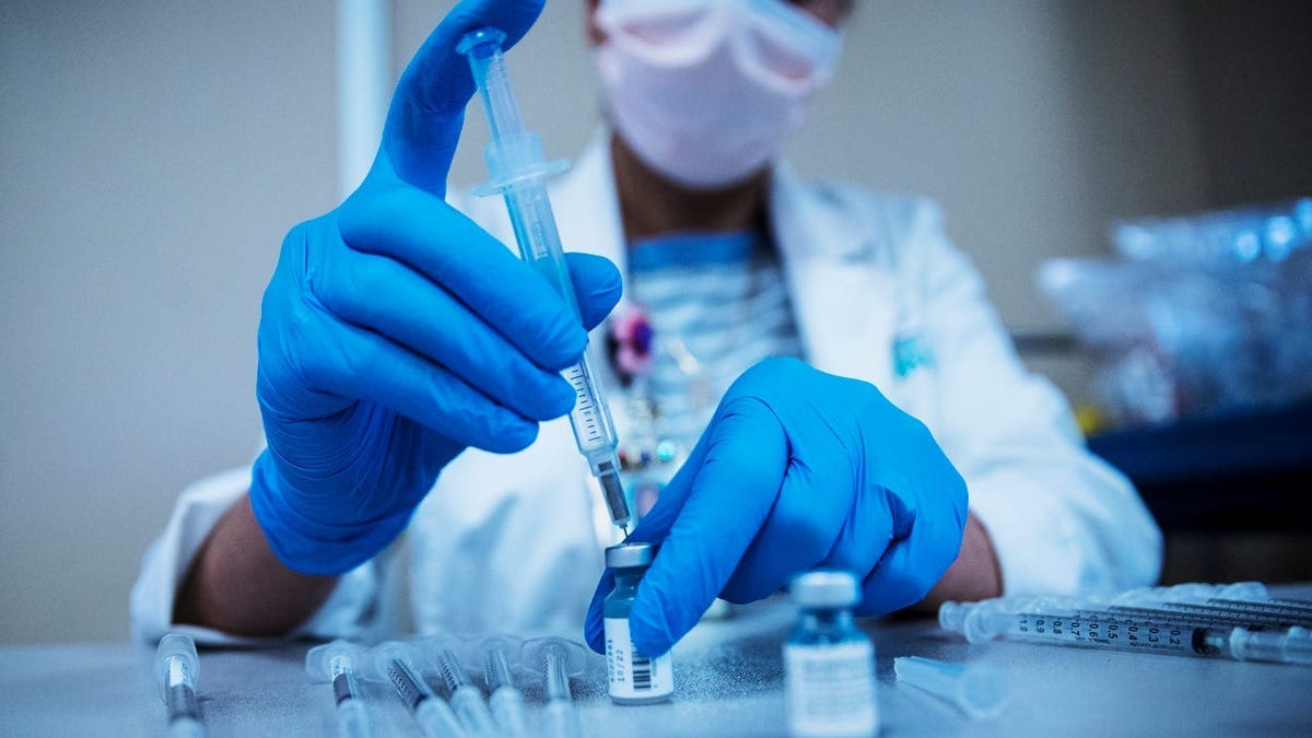 Ann Lee, a pharmacist for Lee Health, prepares COVID-19 vaccine at a vaccination site at Gulf Coast Medical Center in Fort Myers, Florida. Vaccinations have picked up as the delta variant has spread.