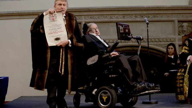 In this March 6, 2017 file photo, Britain's Professor Stephen Hawking is presented with his illuminated Freedom scroll by the Chamberlain of the City of London Peter Kane as he receives the Honorary Freedom of the City of London during a ceremony at the Guildhall in the City of London.