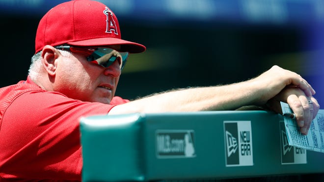 Los Angeles Angels manager Mike Scioscia leans over the dugout rail as he looks on against the Colorado Rockies in the first inning of an interleague baseball game Wednesday, May 9, 2018, in Denver. (AP Photo/David Zalubowski)