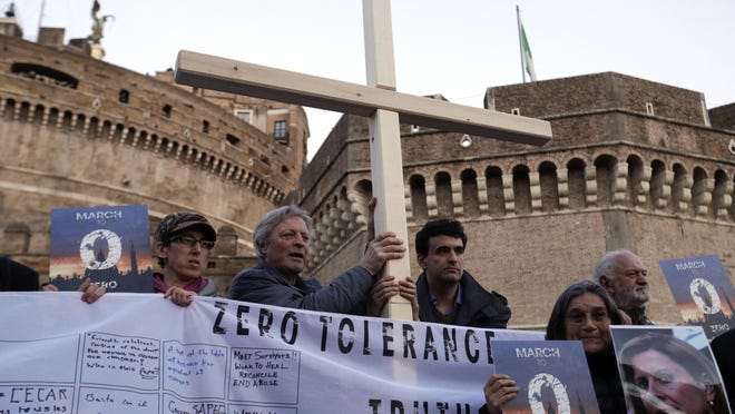 Survivors of sex abuse hold a cross as they gather during a twilight vigil prayer near Castle Sant' Angelo, in Rome, Thursday, Feb. 21, 2019. Pope Francis opened a landmark sex abuse prevention summit Thursday by warning senior Catholic figures that the faithful are demanding concrete action against predator priests and not just words of condemnation. (AP Photo/Gregorio Borgia)
