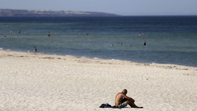 A beachgoer sits in the sun on Glenelg Beach in Adelaide, Australia, Jan. 24, 2019.