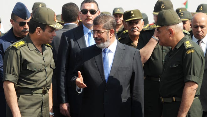 Then-Egyptian president Mohammed Morsi, center, speaks with the minister of defense, Lt. Gen. Abdel Fattah al-Sisi, left, at a military base in Ismailia, Egypt, Oct. 10, 2012.