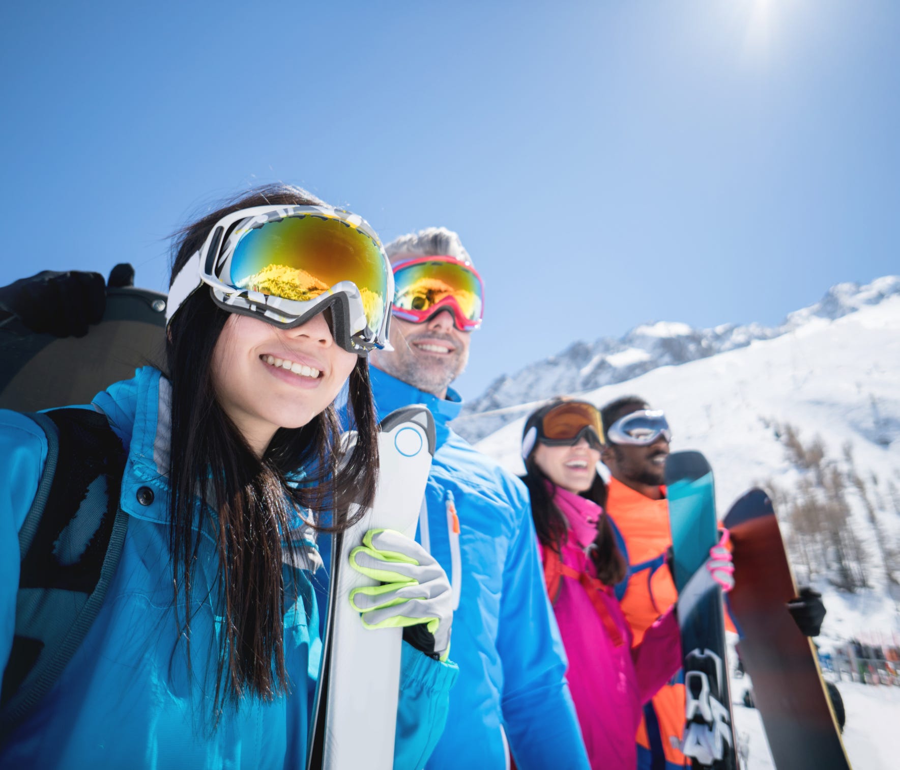Happy group of people skiing and wearing goggles outdoors - winter sports concepts