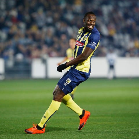 Usain Bolt overruns across the pitch during a...