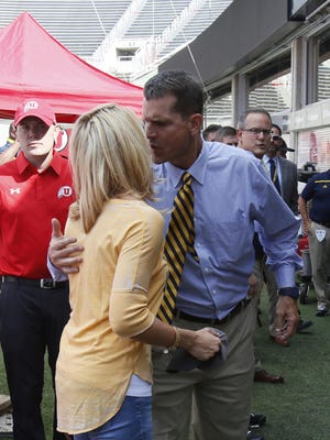 Michigan coach Jim Harbaugh receives a good-luck kiss from his wife, Sarah, before heading to the locker room after arriving at Rice-Eccles Stadium on Thursday in Salt Lake City.