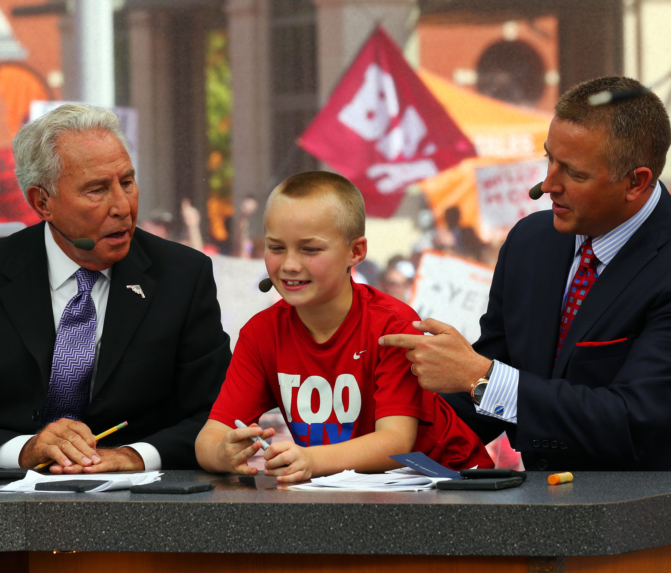 This file photo from 2015 shows Lee Corso, left, with 'College GameDay' partner Kirk Herbstreit, right, and Herbstreit's son, Chase, at Sundance Square in Fort Worth, Texas.