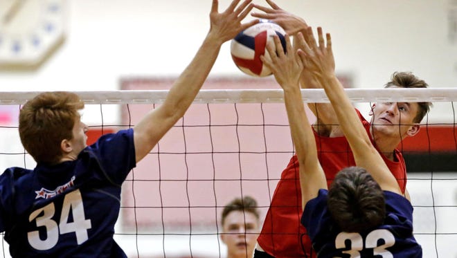 James Hovorka of Neenah hits through the defense of Matt Polfuss (34) and Tim Stadler of Appleton East during a Fox Valley Association volleyball quadrangular Tuesday in Neenah.